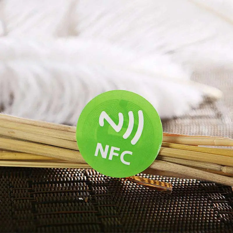 Runder grüner NFC-Aufkleber mit weißem NFC-Symbol auf hellem Untergrund.
