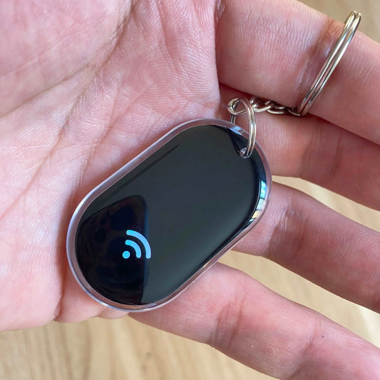 Schwarzer Epoxidharz-NFC-Schlüsselanhänger mit blauem WLAN-Symbol und silbernem Schlüsselring in Hand.