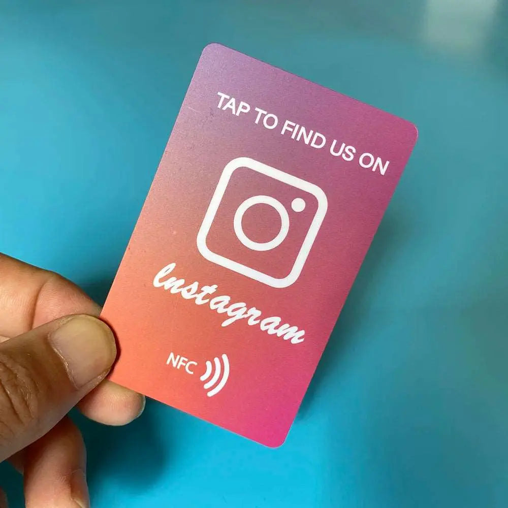 Hand hält rosa Instagram NFC-Karte mit Instagram-Logo und Text „Tap to find us on“.